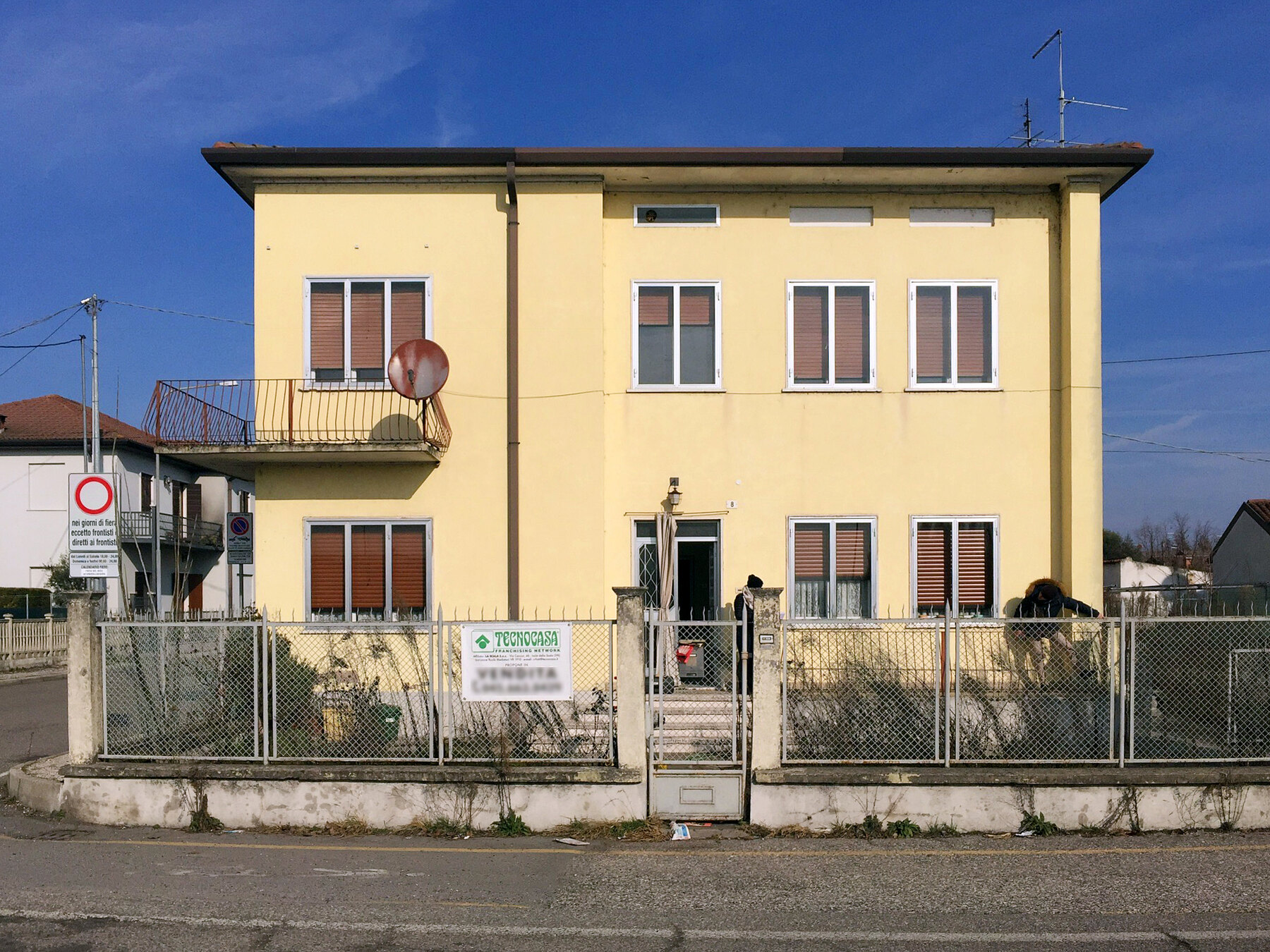 L’edificio residenziale prima dei lavori, con il cartello di vendita sulla recinzione