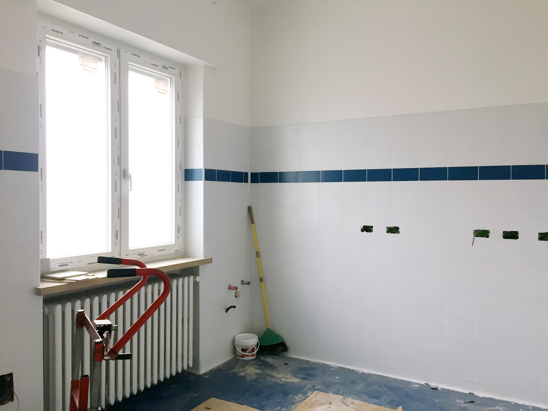 Il rivestimento lavabile in ceramica con fascia blu, posato prima degli arredi