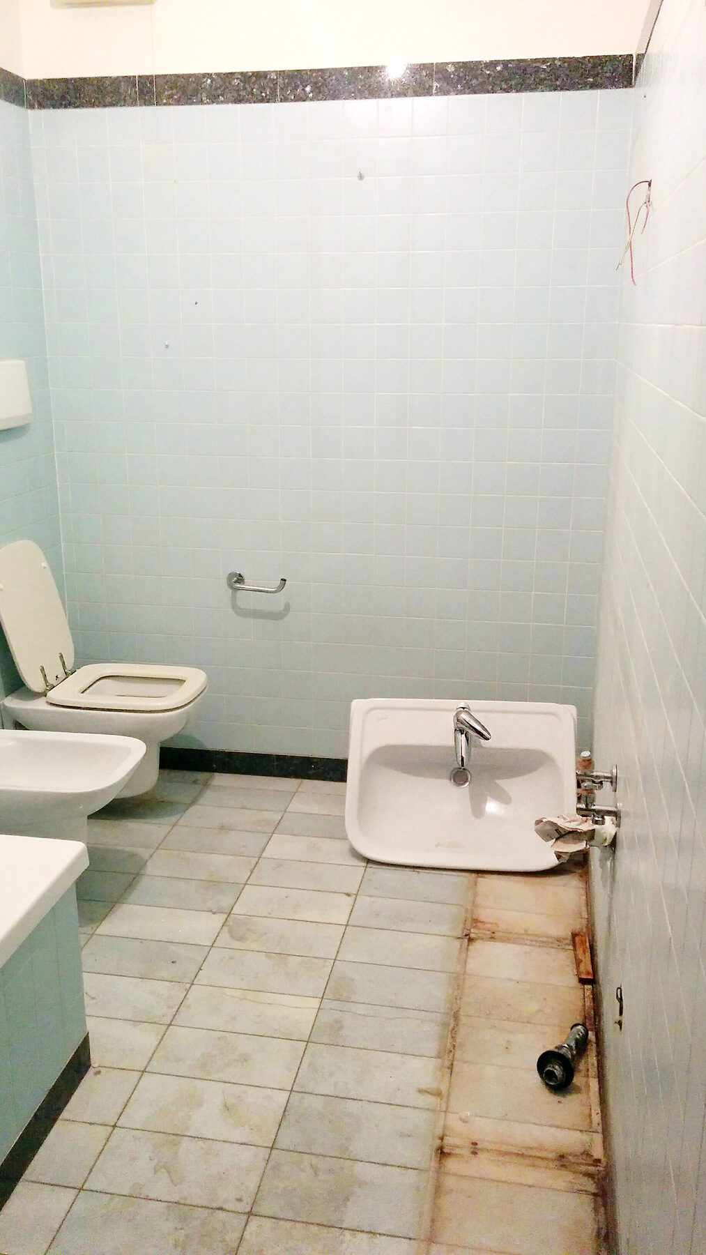 Il bagno di servizio con i sanitari gi&agrave; smontati e i pavimenti da rifare