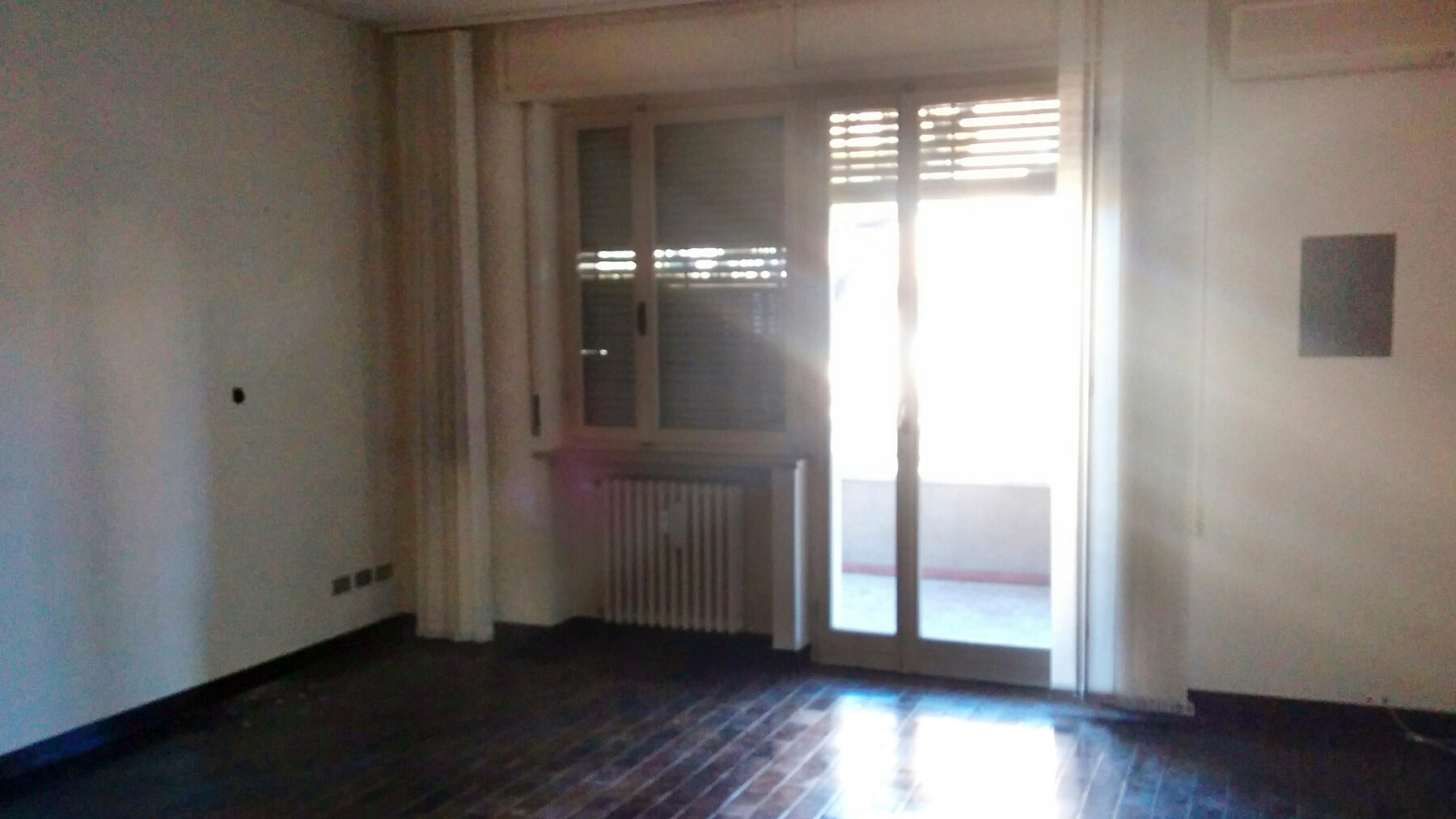 Una delle camere esistenti, con la portafinestra sul terrazzo e il vecchio parquet